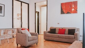 A modern living room with a sofa, armchair, and a wooden coffee table. - Family Apartment City Center - Mirable PM (Milano)