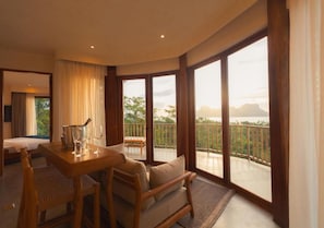 Une chambre d’hôtel avec un balcon, une table à manger avec des chaises, un canapé et un lit.