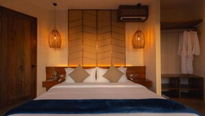 Une chambre à coucher comprenant un lit, des tables de chevet, une armoire en bois et un luminaire suspendu.