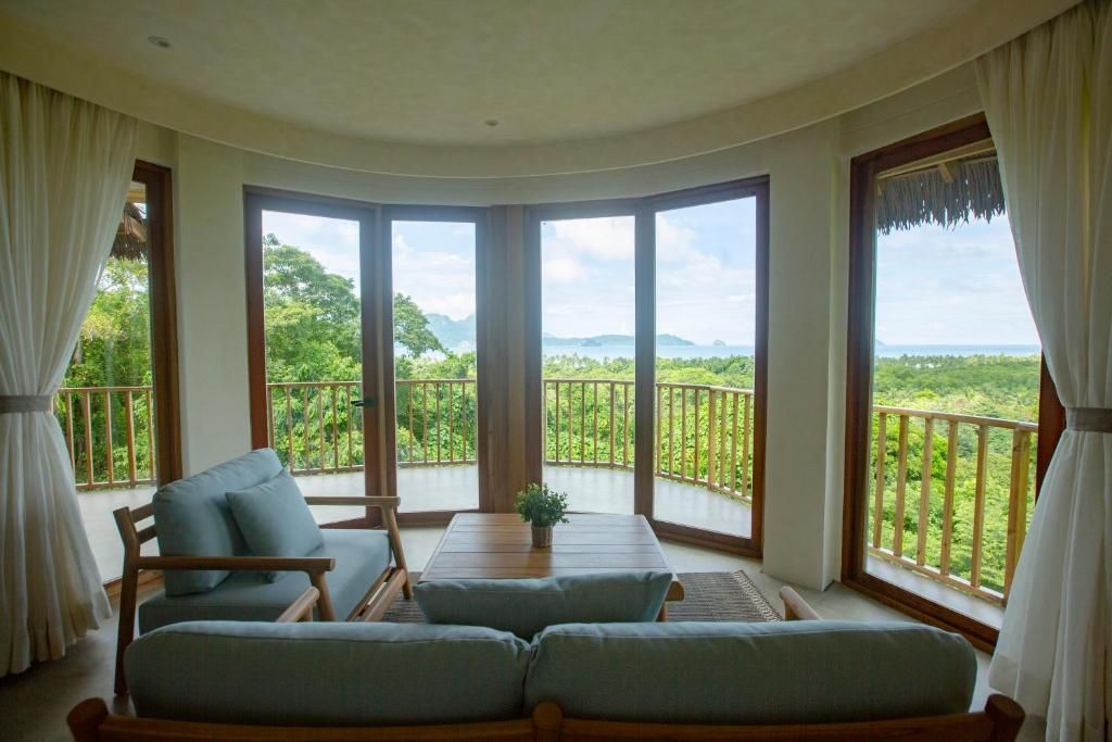 A room with a curved balcony, a sofa, a table, and curtains.