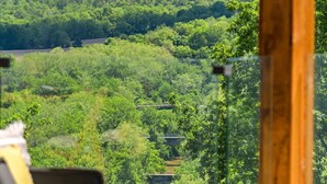 A room with a view of a lush green landscape, including a river and distant mountains.