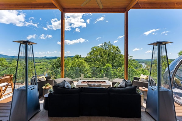 Un área de estar exterior moderna con vistas a un bosque y montañas.