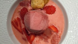 A dessert with ice cream and strawberries on a white plate.