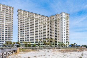 Ein hoch aufragendes Hotel mit zahlreichen Balkonen, Blick auf den Strand und einer Holzpromenade.