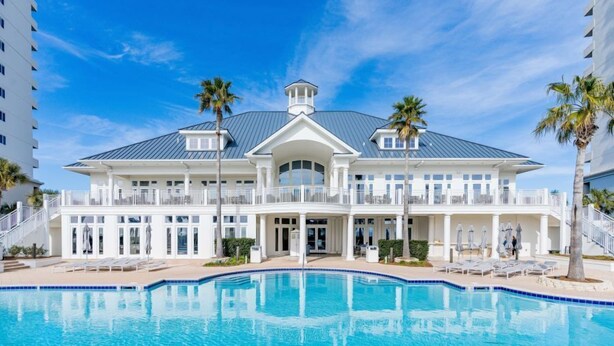 Un grand bâtiment à deux étages, avec une piscine devant.