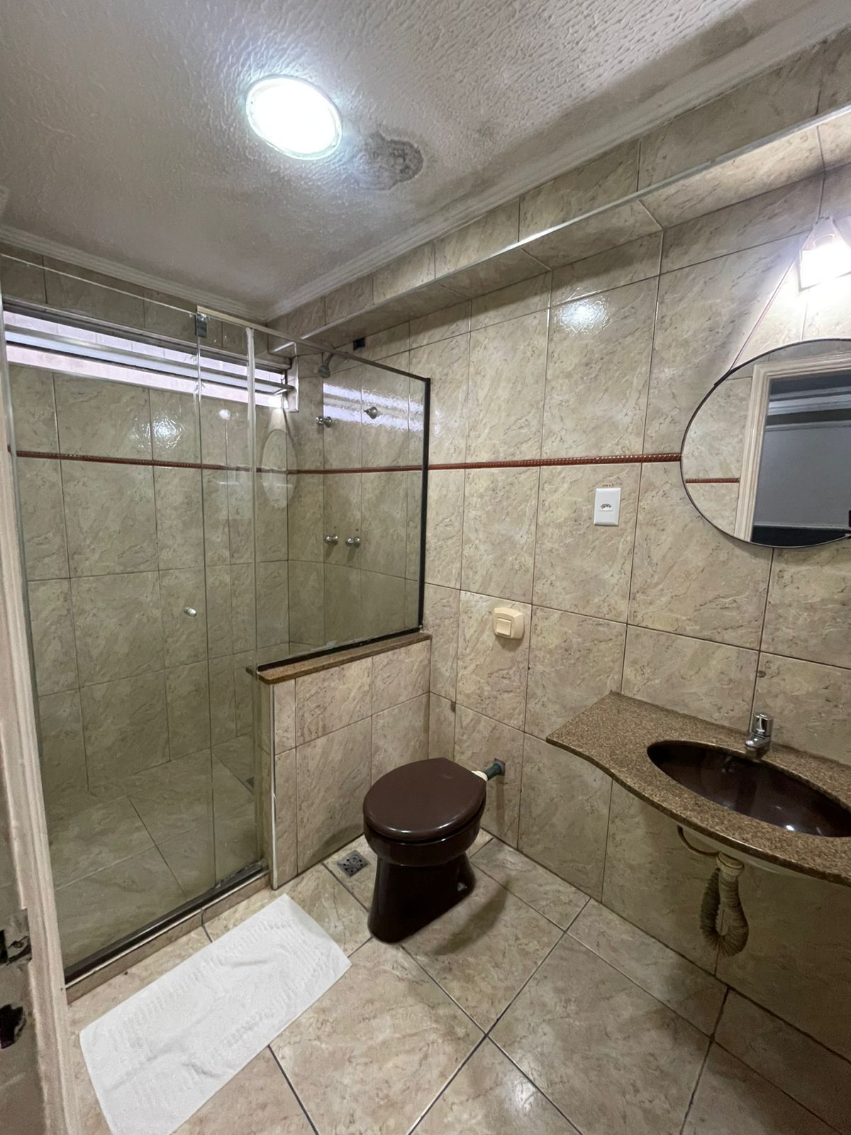 Ein Badezimmer mit einer Duschkabine, einer Toilette und einem Waschbecken mit Spiegel darüber.