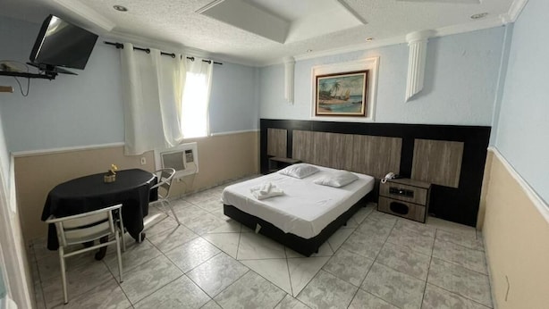 Une chambre d’hôtel avec un lit, un bureau, une chaise, une télévision et un tableau au mur.
