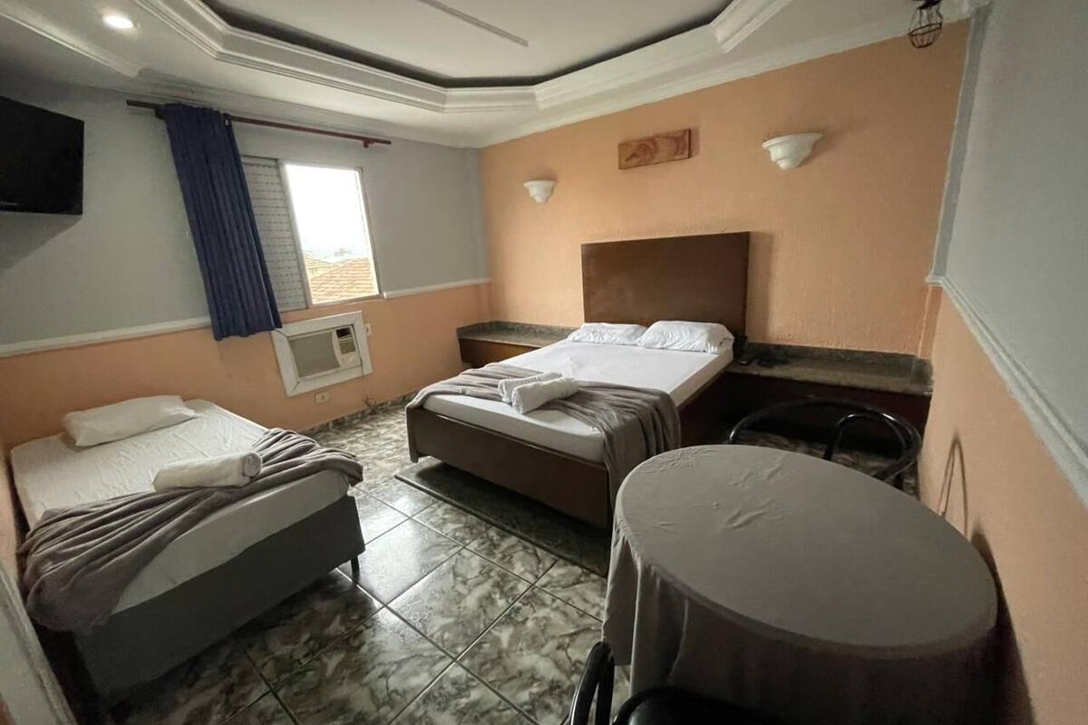 Ένα δωμάτιο με δύο κρεβάτια, ένα μικρό τραπέζι και μια τηλεόραση τοποθετημένη στον τοίχο.