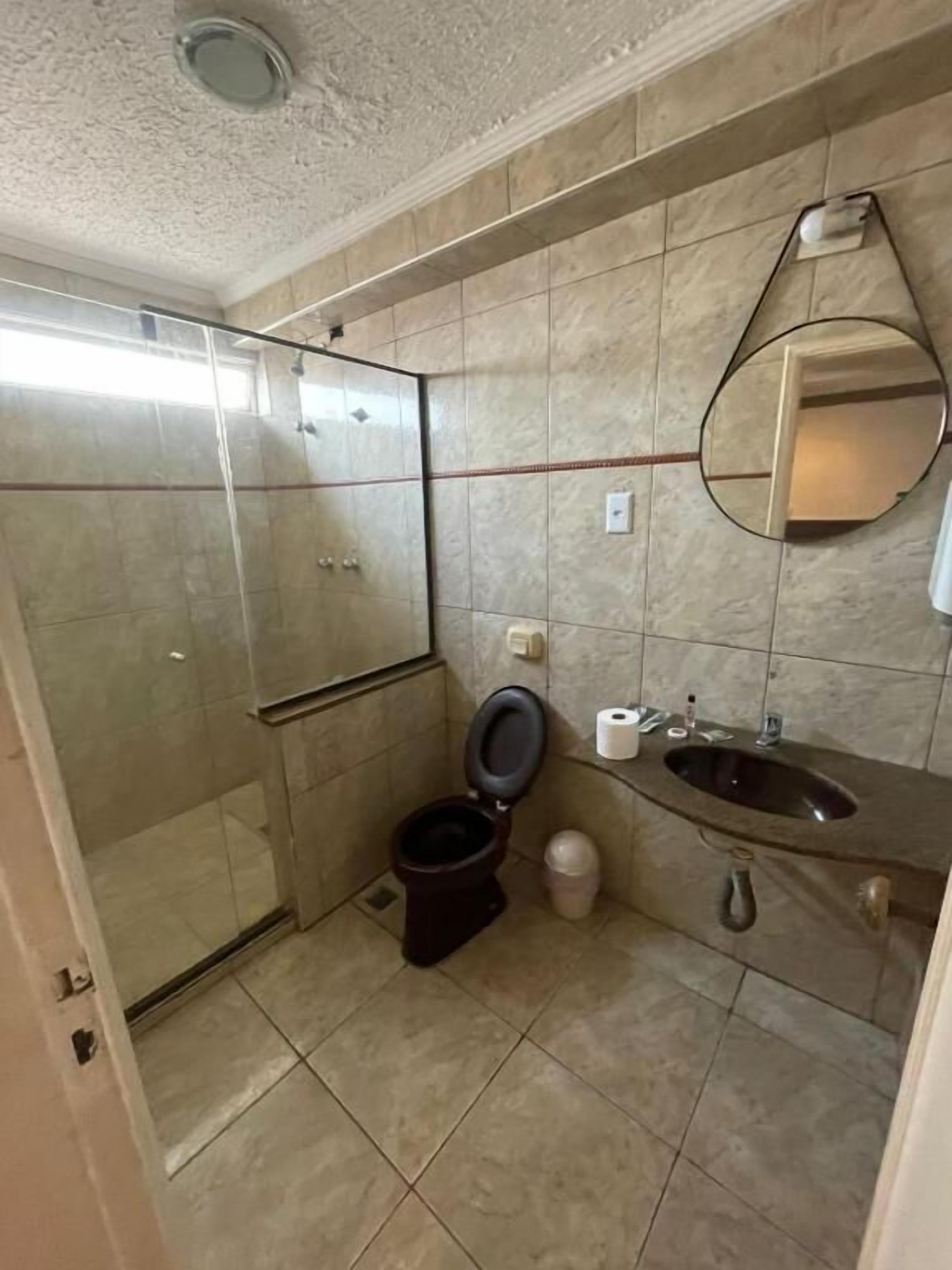 A bathroom with a toilet, sink, and glass shower enclosure.