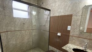 Ein Badezimmer mit einer Duschkabine, einer Toilette, einem Waschbecken und einem Spiegel.