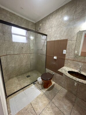 Ein Badezimmer mit einer Duschkabine, einer Toilette, einem Waschbecken und einem Spiegel.