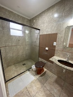 Un baño con ducha de mampara de vidrio, inodoro, lavabo y espejo.