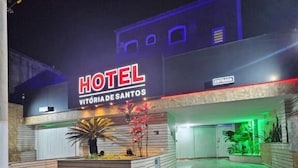 Un hôtel appelé « HOTEL VITORIA DE SANTOS », doté d’une façade moderne, d’une enseigne indiquant l’entrée et d’un hall d’entrée bien éclairé.