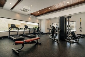 Ein Fitnessstudio mit Laufbändern, einer Bank und Krafttrainingsgeräten.