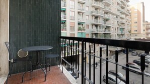 A balcony with a table and chairs, a view of a multi-story building with balconies, and a parking area below. - GuestHost - A comfortable 30 square meters studio, perfect for two people, located on the first floor of a building with an elevator (NOT suitable for people with reduced mobility).The apartment is just steps from Pasteur metro station and within a 10-mi (Milan)