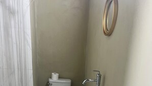 Ein kleines Badezimmer mit Toilette, Waschbecken und Dusche.