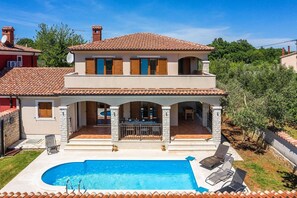 Ein zweistöckiges Haus mit Swimmingpool, Außenbereich und einer überdachten Terrasse.