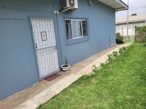 Un immeuble résidentiel à la façade bleue, doté d’une entrée sécurisée et d’un petit jardin.