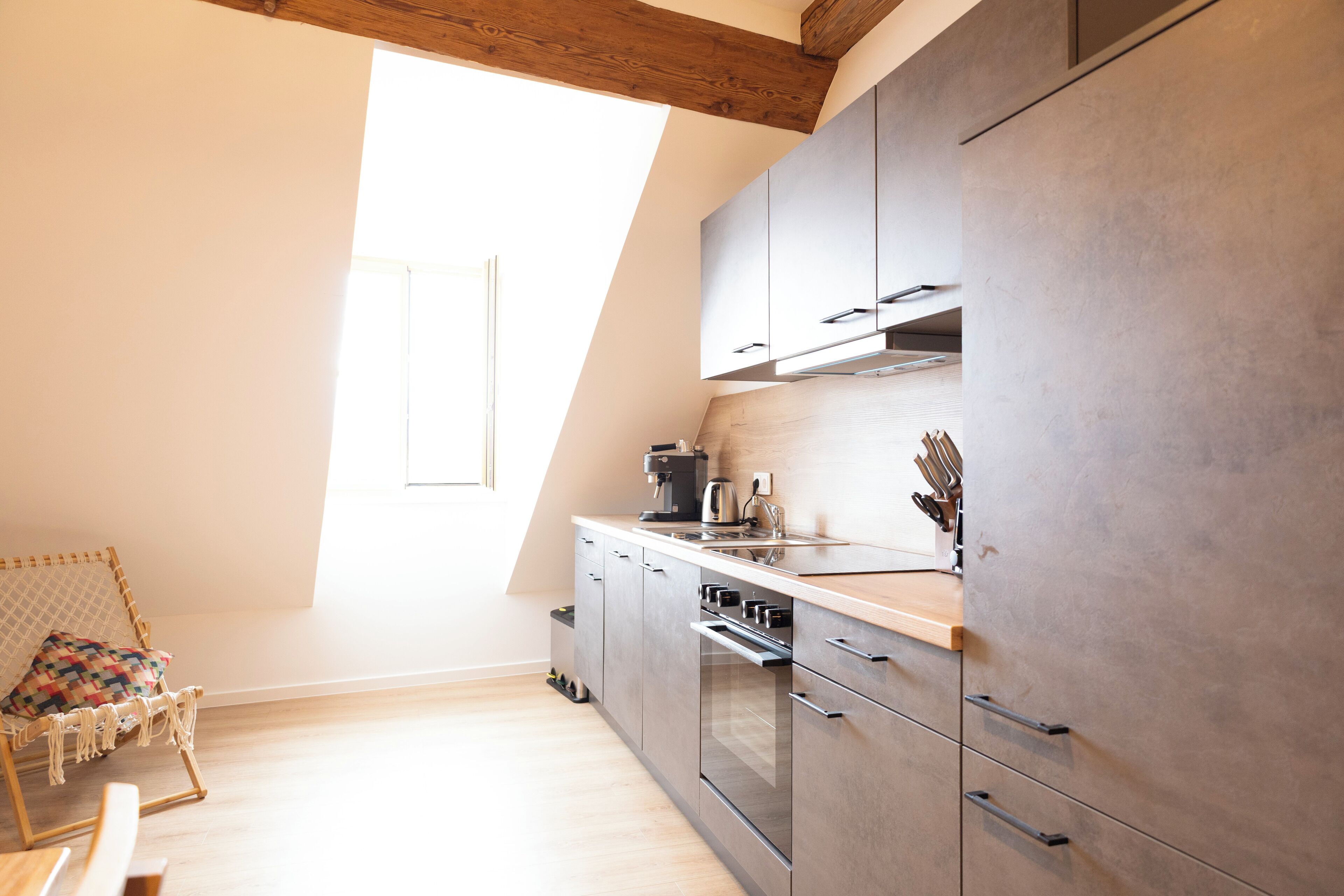 Een moderne keuken met een houten plafond, inbouwmeubels en een raam dat natuurlijk licht binnenlaat.