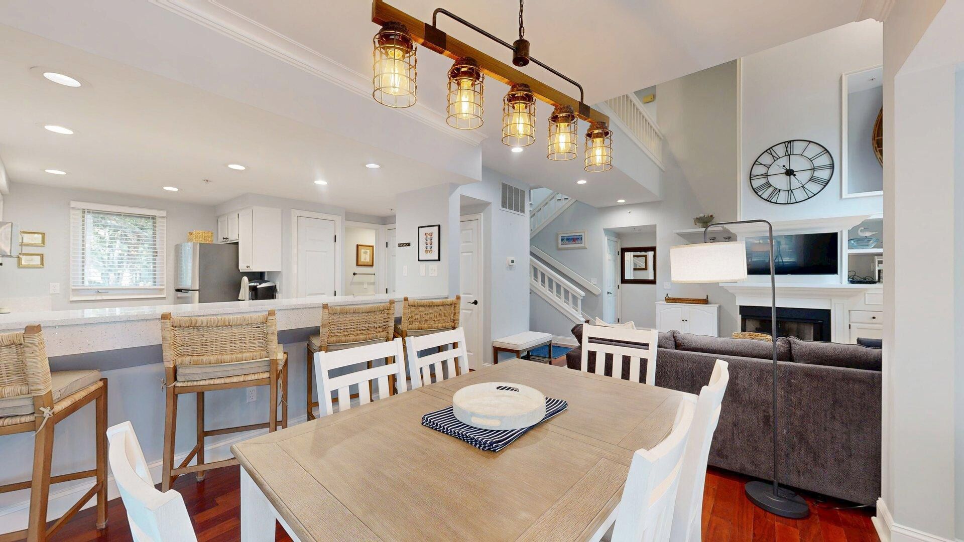 A spacious living area with a dining table, chairs, a sofa, and a staircase leading to another level.
