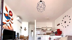 Una sala de estar moderna con televisor, asientos, una cocina y un comedor.