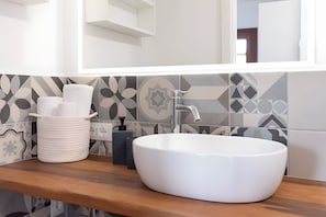 A bathroom with a white sink, a mirror, and patterned tiles.