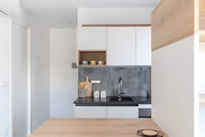 A modern kitchen with white cabinets, a black countertop, and a wooden table.