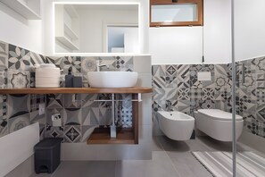 Een moderne badkamer met een vrijstaand badkamermeubel, een toilet en een douchetoilet.