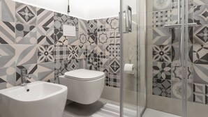 Une salle de bain équipée d’un bidet, de toilettes et d’une douche à parois en verre.