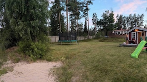 Une vue sur le lac avec un chalet, un toboggan vert et un bateau sur l’eau.