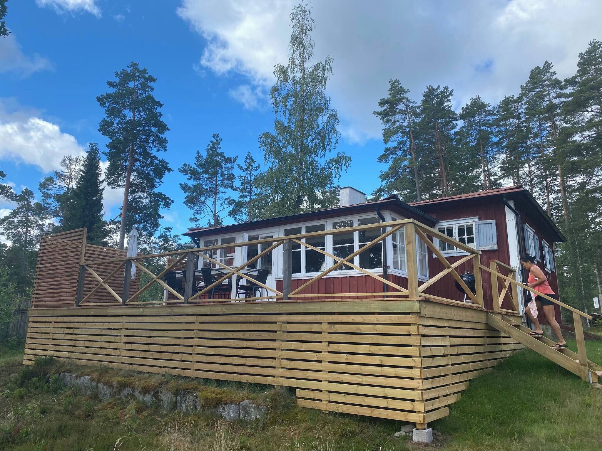Una cabaña de madera con terraza, rodeada de árboles.