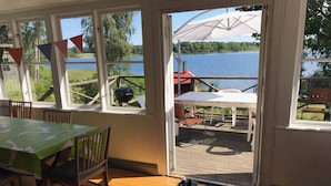 Une pièce comprenant une table et des chaises, avec vue sur un lac, et une terrasse aménagée avec du mobilier d’extérieur.