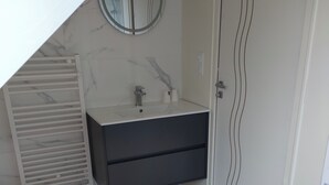 A bathroom with a white sink, dark cabinet, marble wall, and a towel on the floor. - Room with outdoor spa unlimited access (Porcaro)