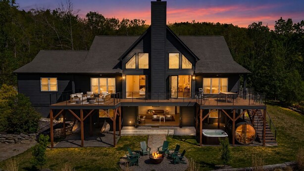 Une maison à deux étages dotée d’un patio couvert, d’un espace salon extérieur et d’un jacuzzi.