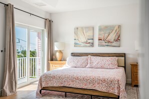 Ein Schlafzimmer mit einem Bett, einem Nachttisch, einer Lampe und zwei Segelbootbildern an der Wand.