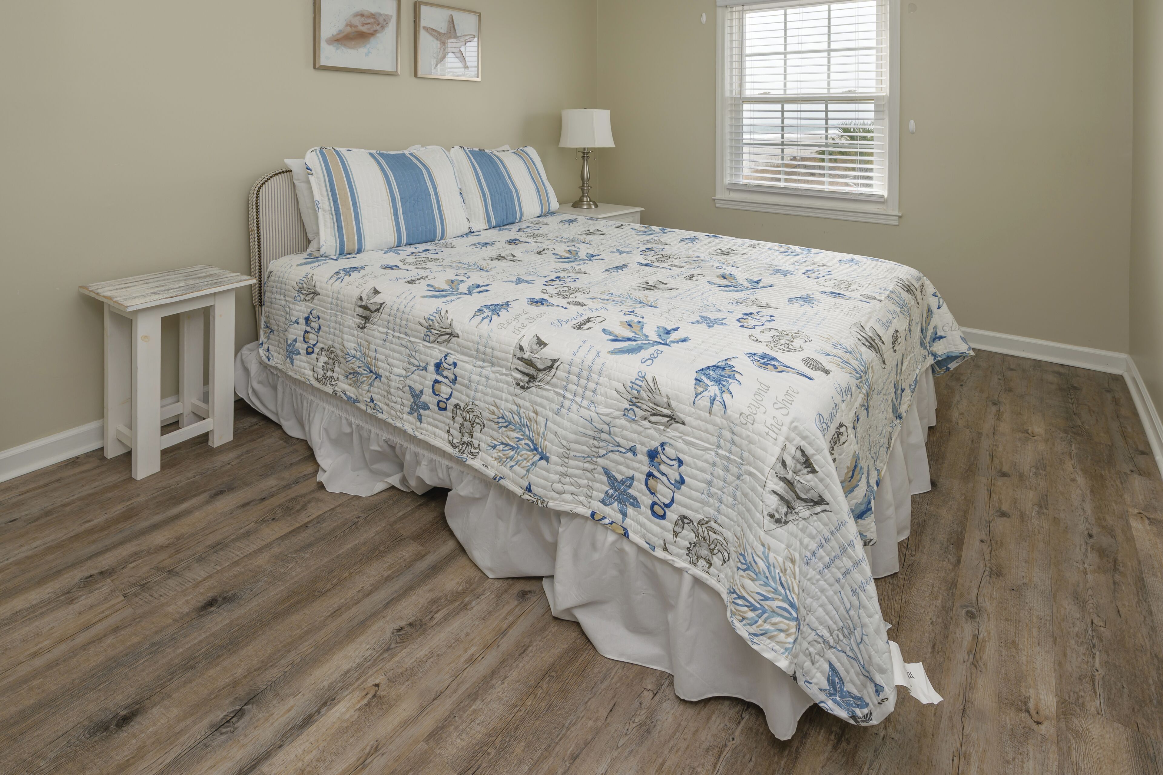 A bedroom with a bed, a nightstand, a lamp, and a window with blinds.