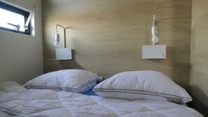 A bedroom with a wooden headboard, two bedside lamps, and a window with blinds.