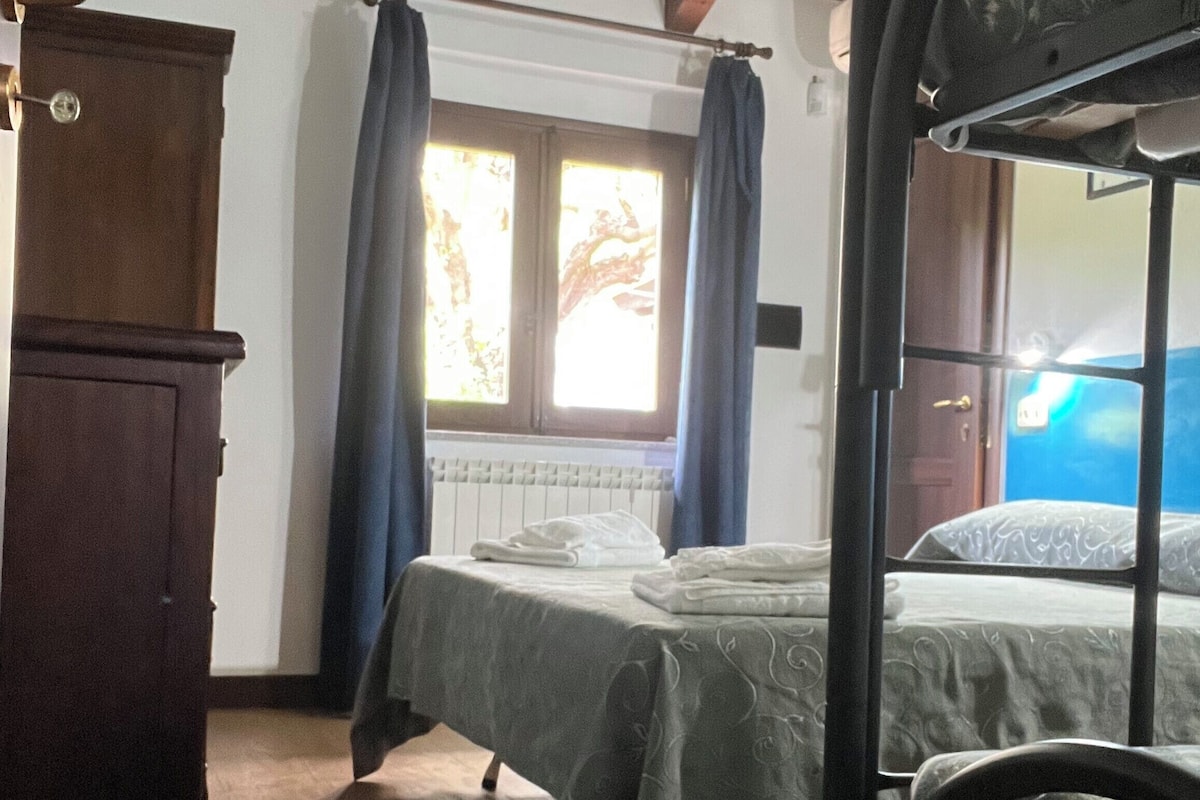 Ein Zimmer mit einem Etagenbett, einem Holzschrank, einem Fenster mit Vorhängen und einem Heizkörper.