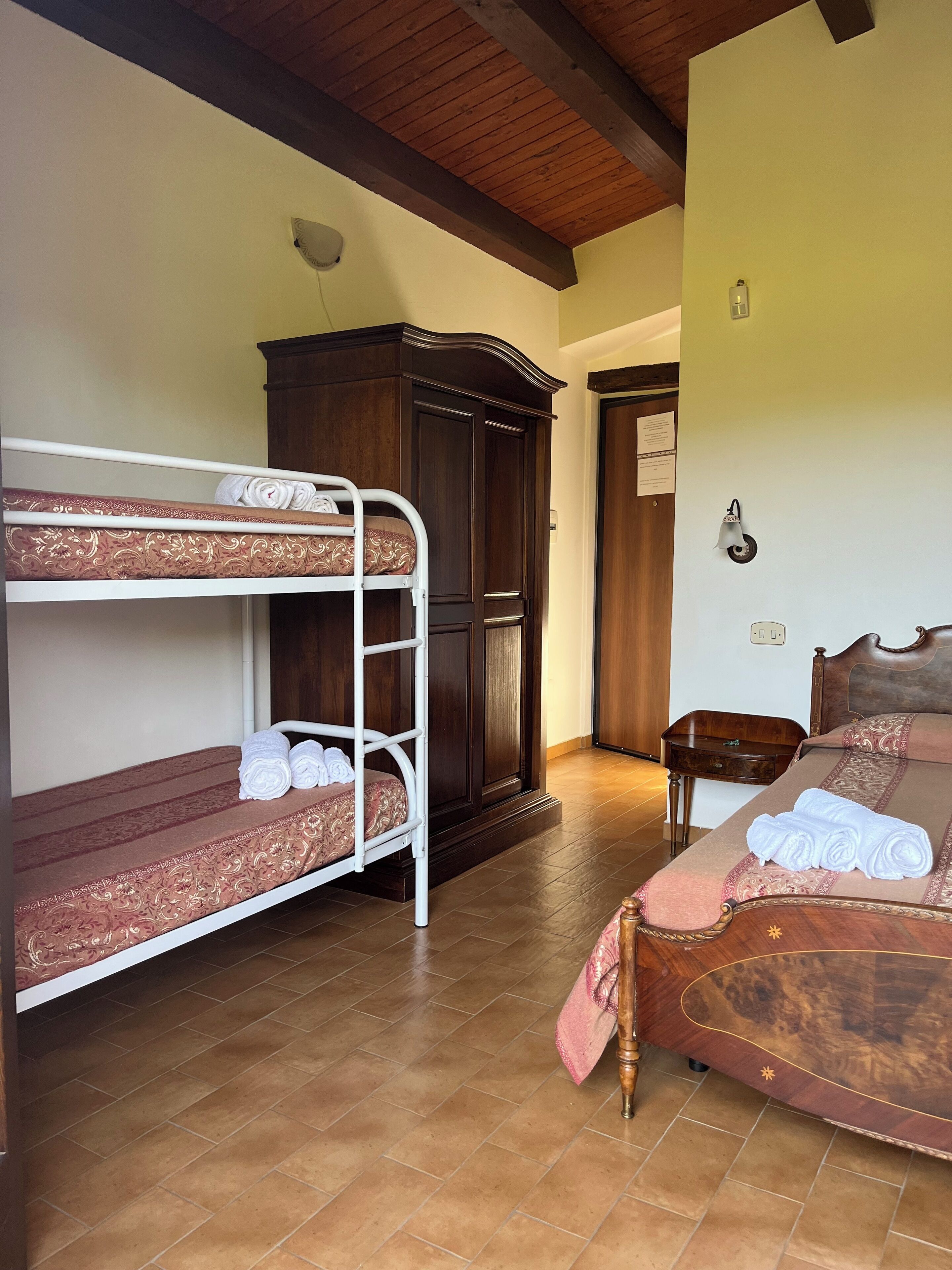 Ein Schlafzimmer mit Etagenbett, einem Holzschrank, einem Nachttisch und einem Bett mit gemustertem Bettbezug.