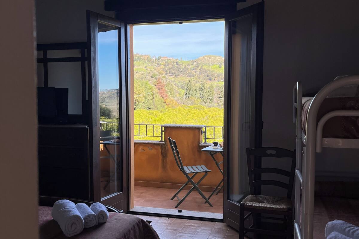 Ein Schlafzimmer mit Bett, Stuhl, Tisch und Blick auf einen Balkon mit Stuhl und Tisch.