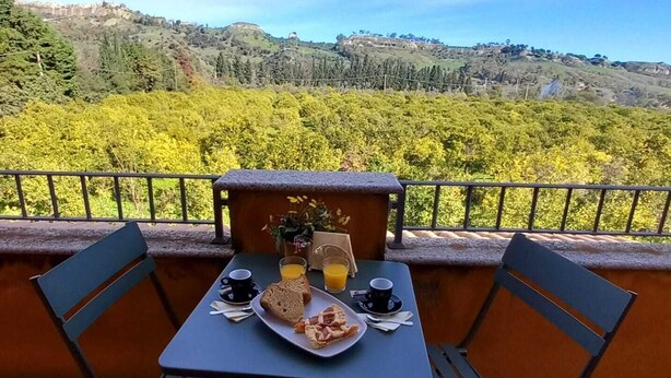 Een tafel met een ontbijtje op een balkon met uitzicht op een weelderig landschap.