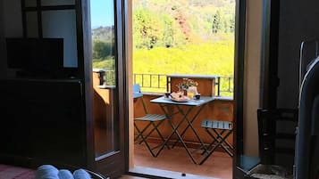 A room with a bed, a table with chairs, and a balcony with a table and chairs.