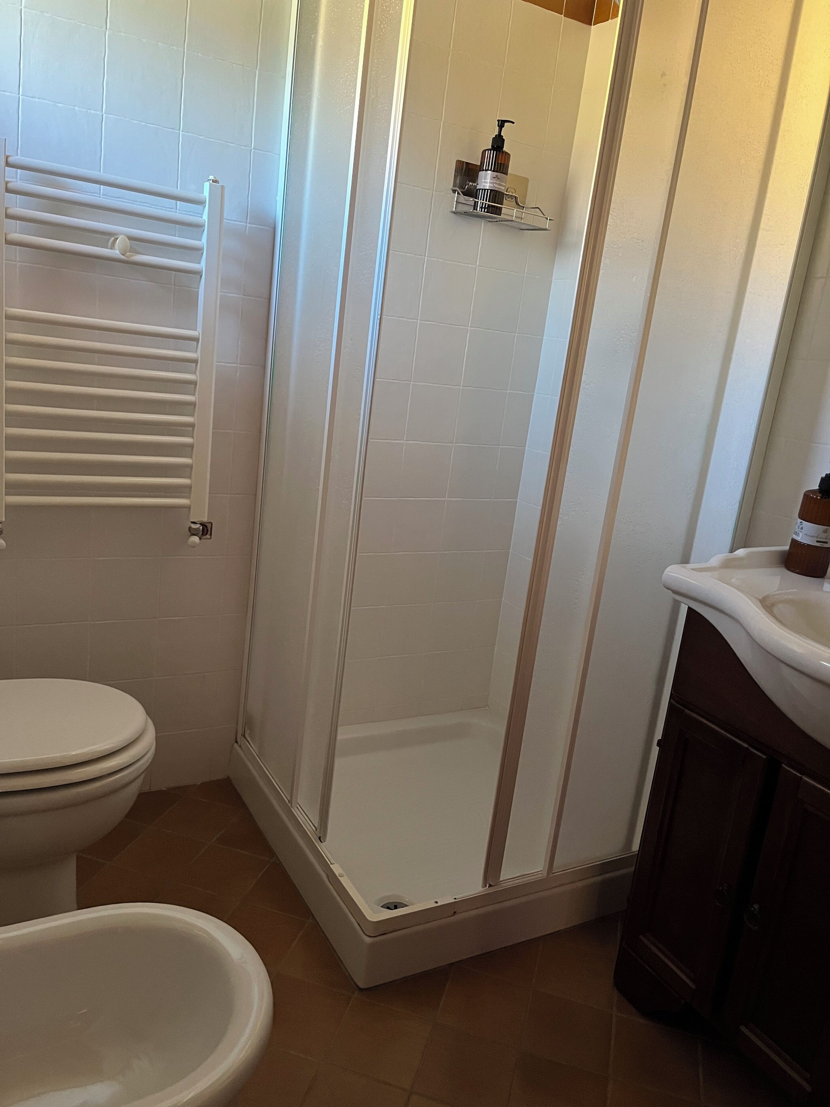 Un bagno con il water, uno spazio doccia e un lavandino.