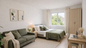 Quarto moderno com um sofá verde, uma cama com manta verde, uma escrivaninha com um laptop e uma janela com cortinas.