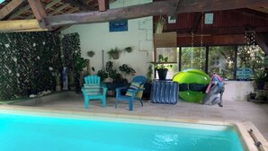 Un área de piscina con una piscina azul cristalina, rodeada de sillas y plantas en macetas.