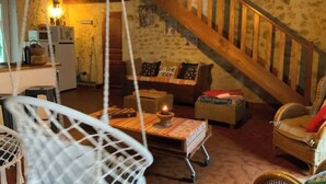 Un interior rústico con una escalera de madera, una zona de comedor con mesa y sillas, y una cocina con electrodomésticos.