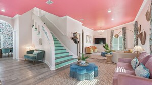 Un salon spacieux avec un escalier, une grande télévision et un coin salon confortable.