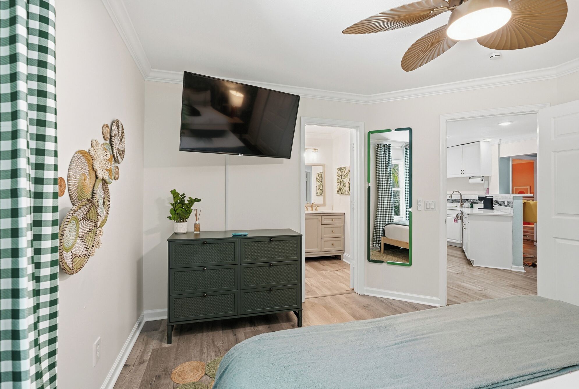 A bedroom with a bed, a dresser, a television, and a ceiling fan.