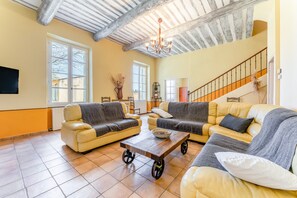 Ein Wohnzimmer mit zwei Sofas, einem Couchtisch, einer Chandelüster und einer Treppe.