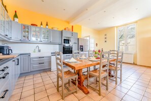 Une cuisine moderne avec des meubles de couleur grise, une table à manger en bois et un sol carrelé.
